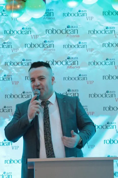 Speaker with a microphone before a Roboclean backdrop